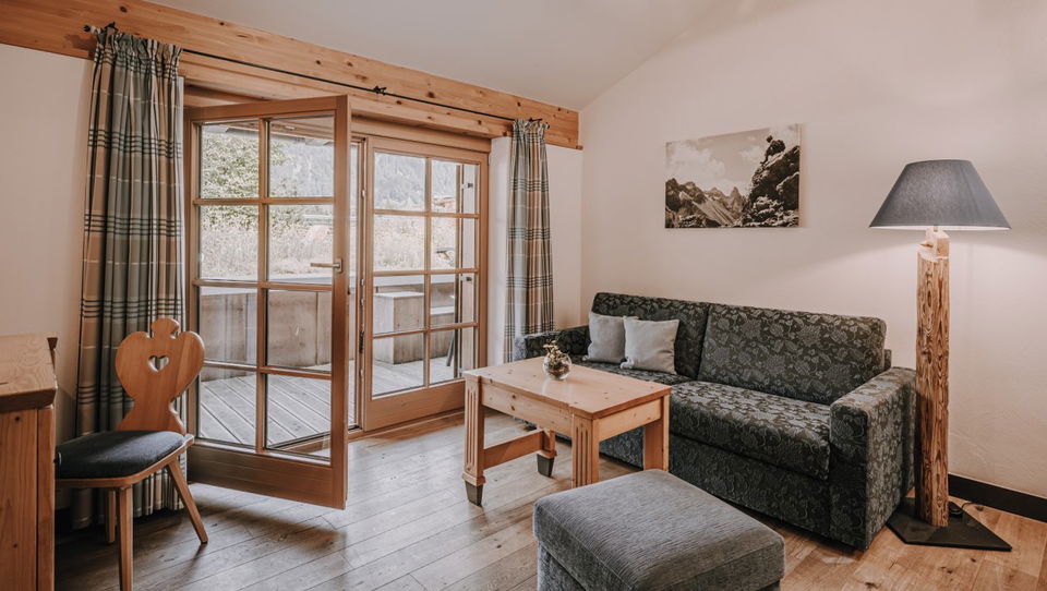 Wohnraum mit Sitzmöbeln und Balkontür in der Suite Ifen.