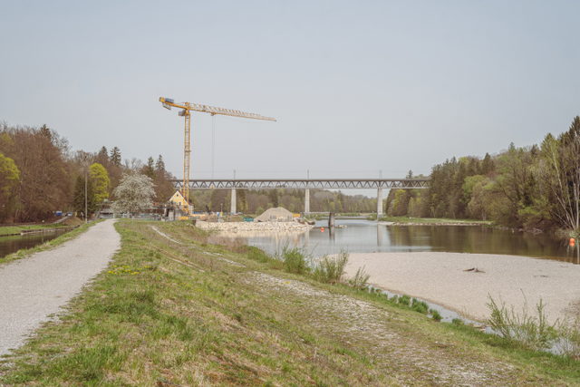 Isarufer mit Blick zur Großhesseloher Brücke und einer Baustelle am Fluss