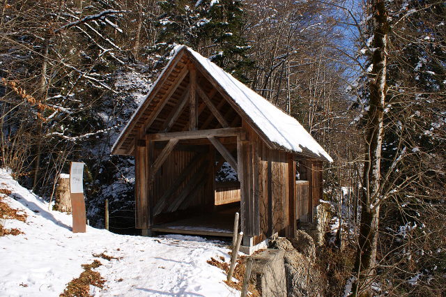 Schneebedeckte Kommabrücke aus Holz bei Hittisau