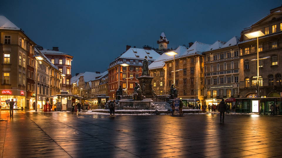 Beleuchtete Häuser und Erzherzog-Johann-Brunnen am Grazer Hauptplatz bei Nacht