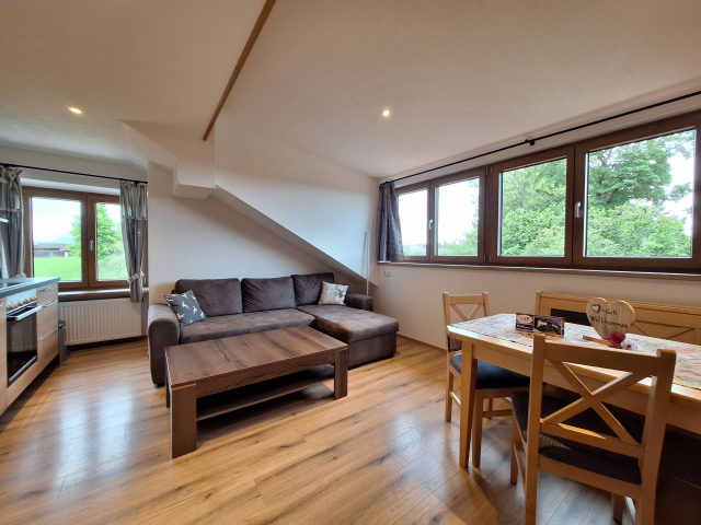 Wohnküche mit Ecksofa, Esstisch und großen Fenstern