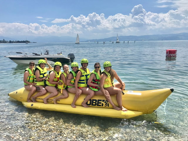 Gruppe mit Schwimmwesten auf einem gelben Banana-Ride am Seeufer