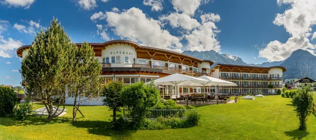 Hotel Alpenhof Oberstdorf mit Garten und Terrasse unter blauem Himmel