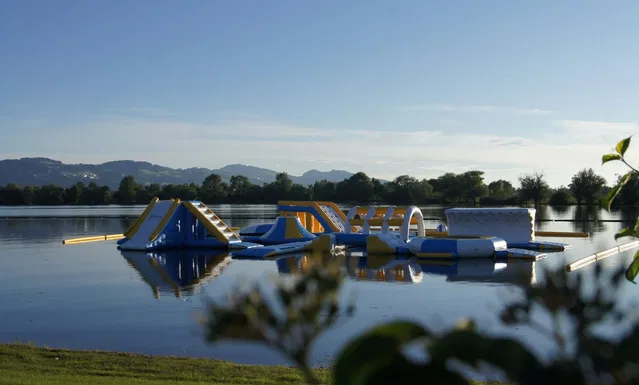 Wasserpark-Inflatables auf einem See mit Bergen im Hintergrund