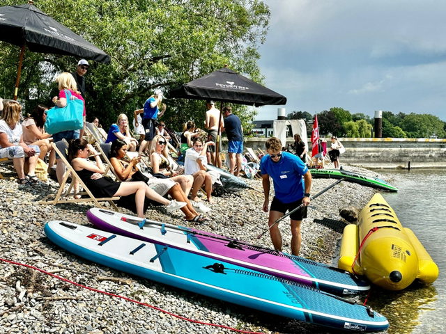 Wassersportausrüstung, Liegestühle und Gäste am Kiesufer in Kressbronn