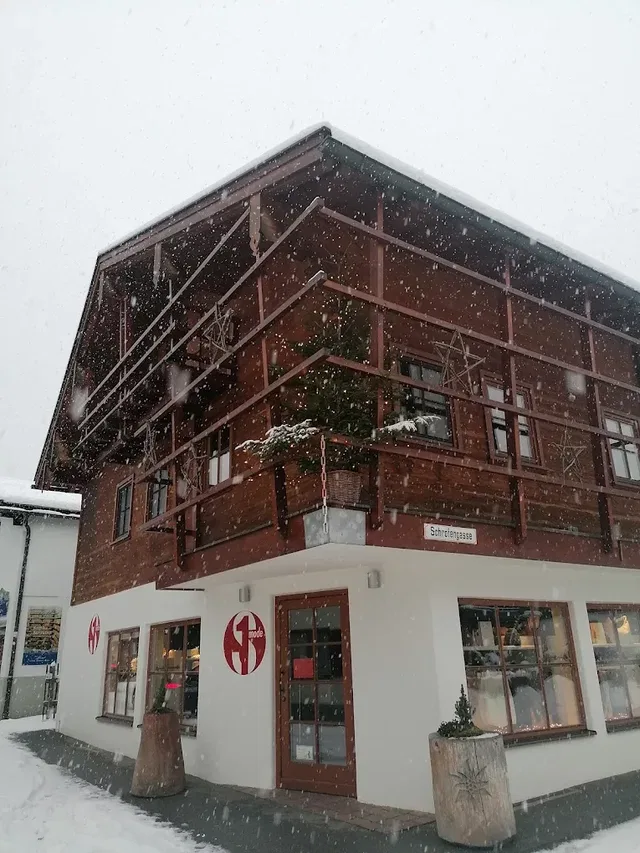Holzchalet im Schneefall mit Balkon über dem Eingang