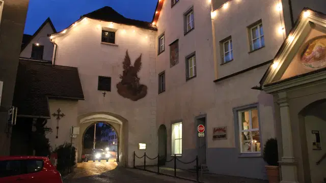 Beleuchtetes Oberes Tor in Bludenz mit Durchfahrt und Wandbild in der Abenddämmerung. Ortsmotiv zur Ausflugsplanung.