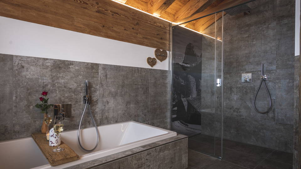 Badezimmer mit Badewanne, Glasdusche und Holzdecke