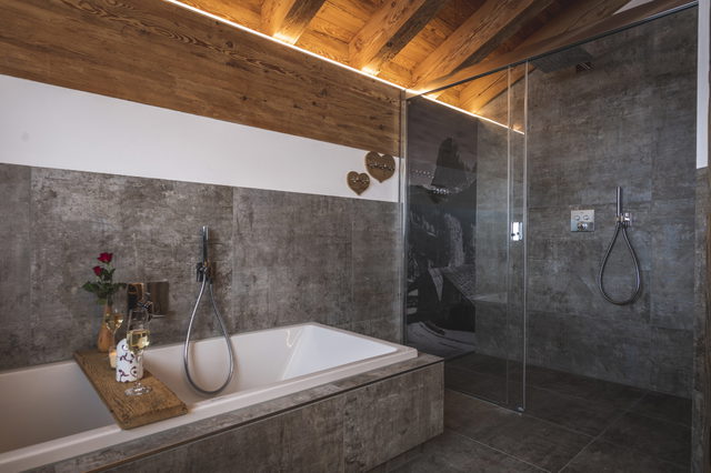 Badezimmer mit Badewanne, Glasdusche und Holzdecke