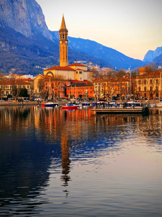 Uferpromenade von Lecco mit Glockenturm von San Nicolo und Bergen im Abendlicht