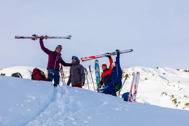 Skitourengruppe mit Skiern auf einem verschneiten Gipfel