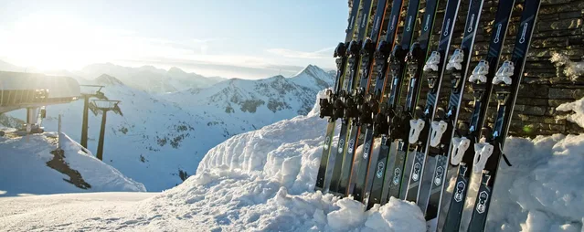 Skier im Schnee vor verschneiten Bergen bei Sonnenlicht