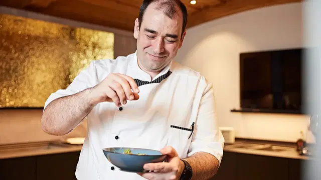 Küchenchef würzt eine Schale in einer modernen Küche.