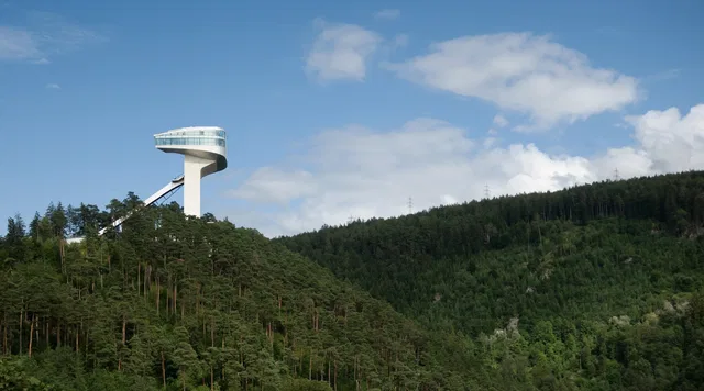 Moderner Aussichtsturm über einem bewaldeten Berghang