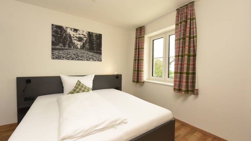 Einzelzimmer mit Bett, Fenster und Landschaftsbild