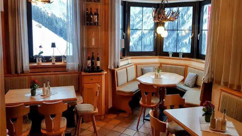 Gastraum der Pizzeria La Marmotta mit Holzmöbeln und Blick auf die Berge.