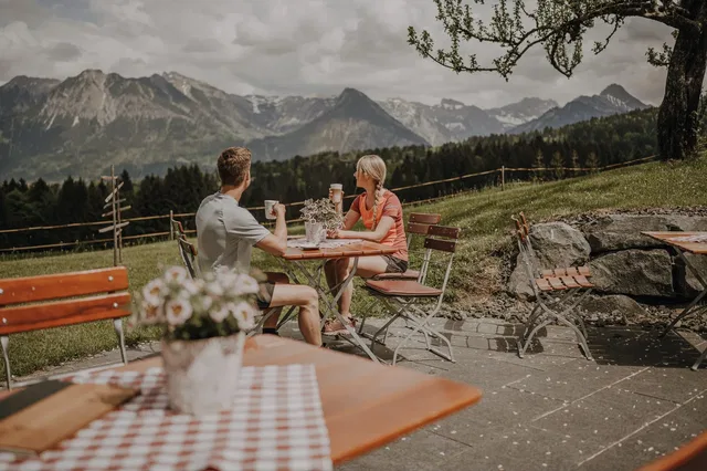 Gäste auf der Terrasse vor dem Bergpanorama.