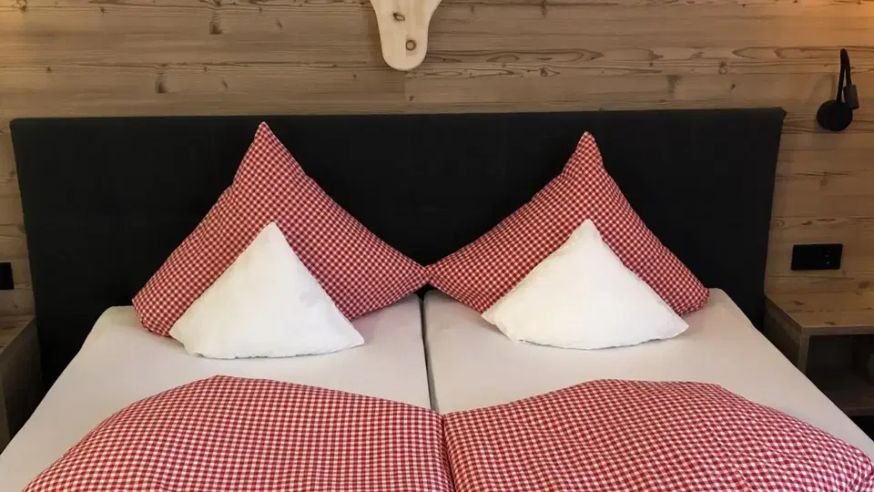 Doppelbett mit rot-weiß karierter Bettwäsche