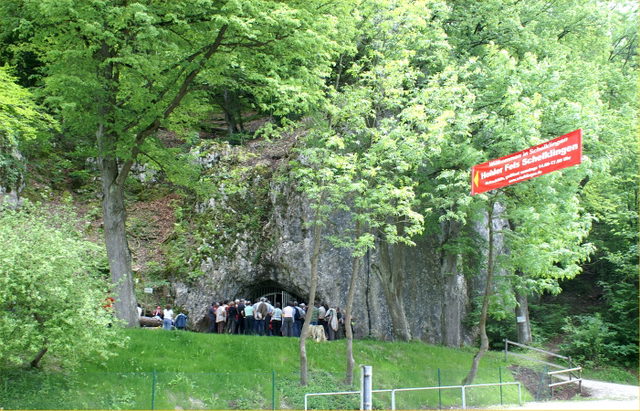 Bewaldeter Hohle Fels bei Schelklingen mit Höhleneingang und Besuchergruppe