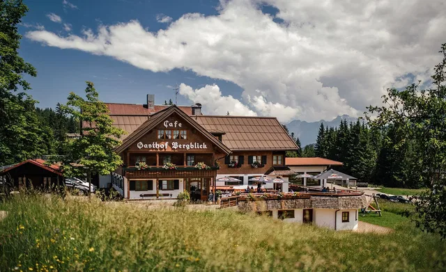 Gasthof Bergblick mit Sonnenterrasse vor grünen Wiesen und Bergen