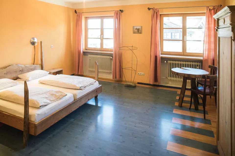 Zimmer Camel mit Doppelbett aus Holz und zwei Fenstern