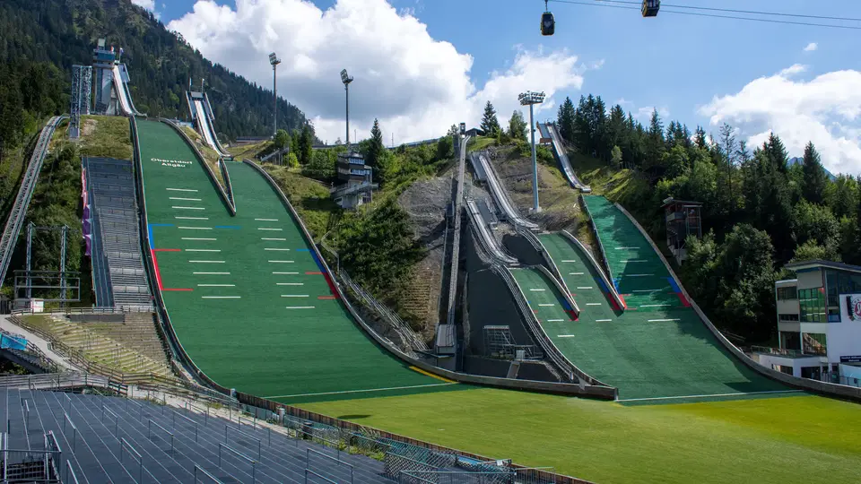 Skisprungschanzen der ORLEN Arena mit grünen Matten und Seilbahngondeln.