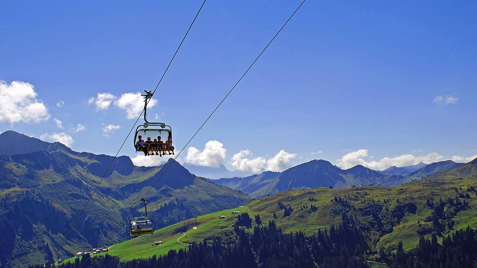 Uga-Express in Damüls mit besetzten Sesseln über grünen Berghängen