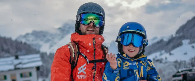Skilehrer und Kind mit Skibrillen im verschneiten Skigebiet