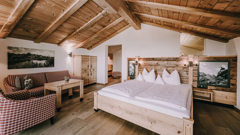 Doppelbett und Sitzecke unter Holzbalken in der Suite Alpenglühen.
