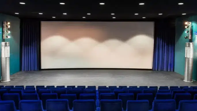 Kinosaal mit blauen Sitzreihen und leerer Leinwand