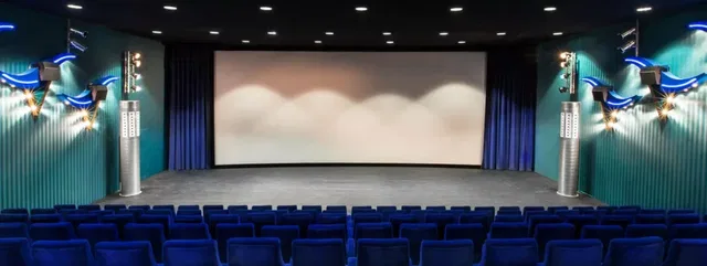 Kinosaal mit blauen Sitzreihen und leerer Leinwand