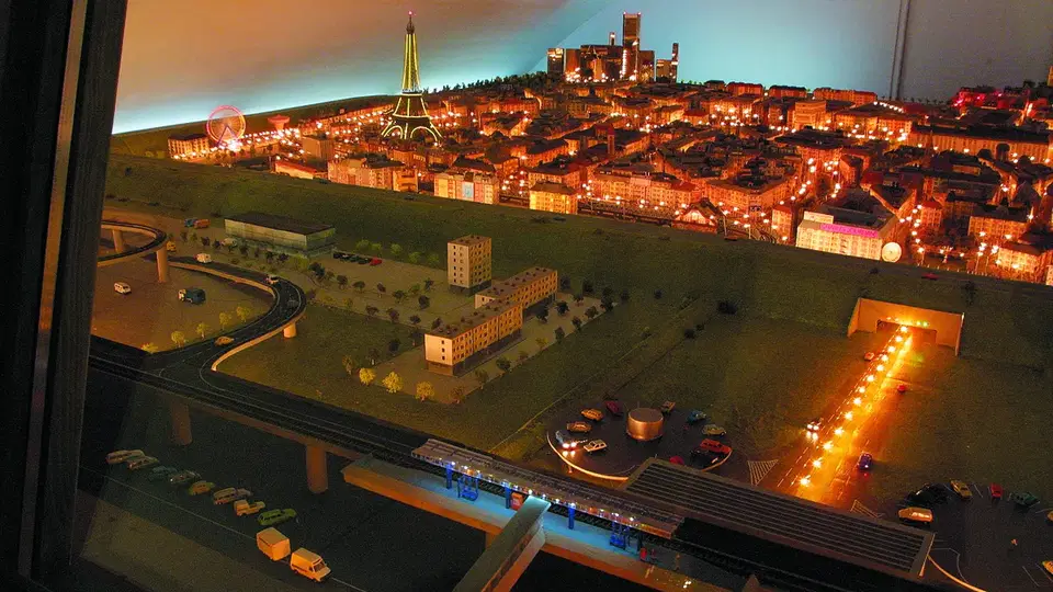 Modellstadt bei Nacht mit Eiffelturm-Nachbildung und Straßennetz in Miniaturform.