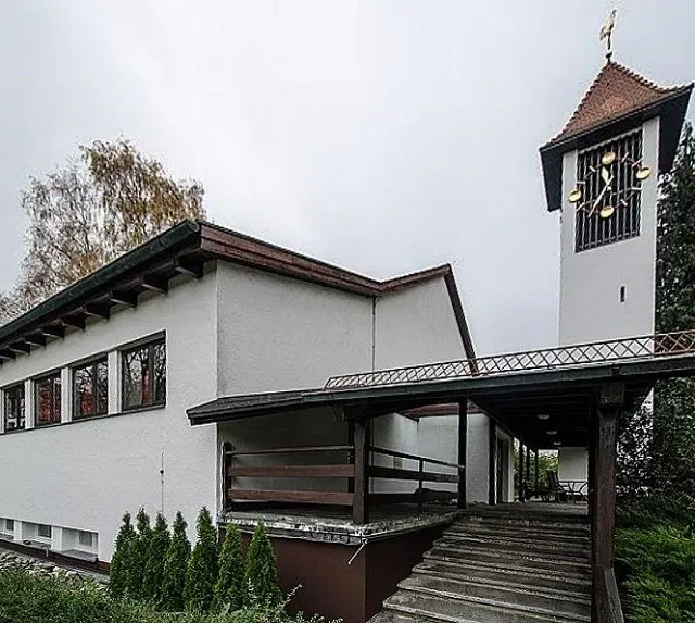 Petruskirche Kattenhorn mit gläsernem Eingang, frei stehendem Glockenturm und Zugang über eine Treppe.