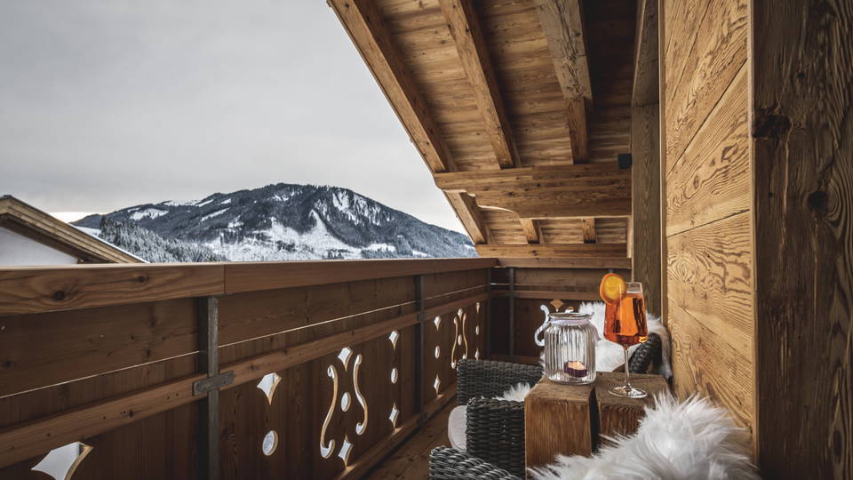 Möblierter Holzbalkon mit Blick auf den verschneiten Berghang