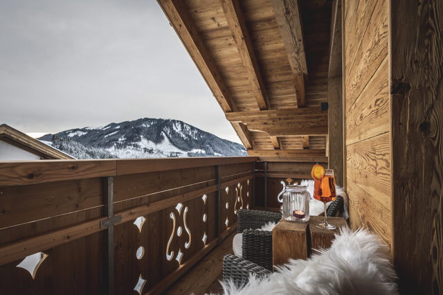 Möblierter Holzbalkon mit Blick auf den verschneiten Berghang