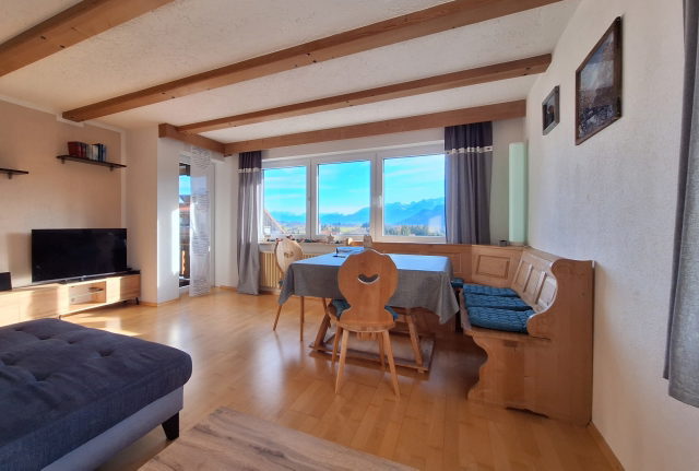 Wohnzimmer der Ferienwohnung Mibbadinn mit Sofa, Esstisch und Bergblick