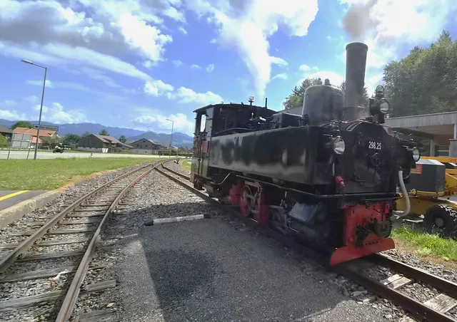 Historische Dampflok auf Gleisen am Bahnhof bei sonnigem Himmel