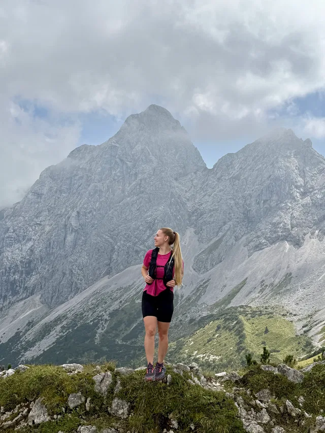 Frau beim Bergwandern auf felsigem Grat mit Bergpanorama