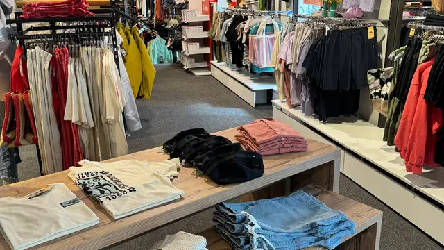 Freizeitbekleidung an Ständern und auf Verkaufstischen