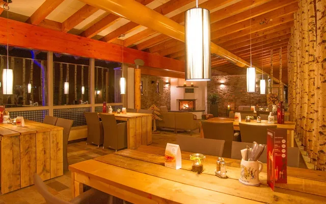 Gemütliches Restaurant mit Holzbalken, Birkenstützen und warmem Licht.