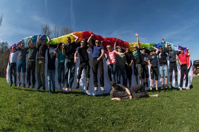 Große Gruppe hält bunten Regenbogen-Schirm im Freien