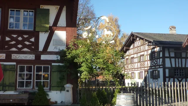 Zwei Fachwerkhäuser mit grünen Fensterläden, Garten und Holz-Zaun.