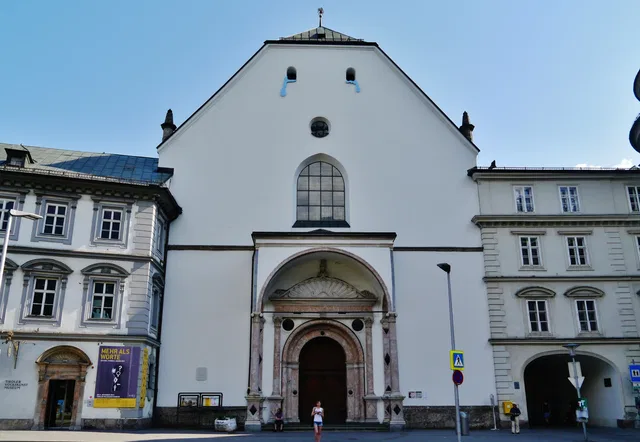 Weiße historische Museumsfassade mit verziertem Portal und großem Rundbogenfenster