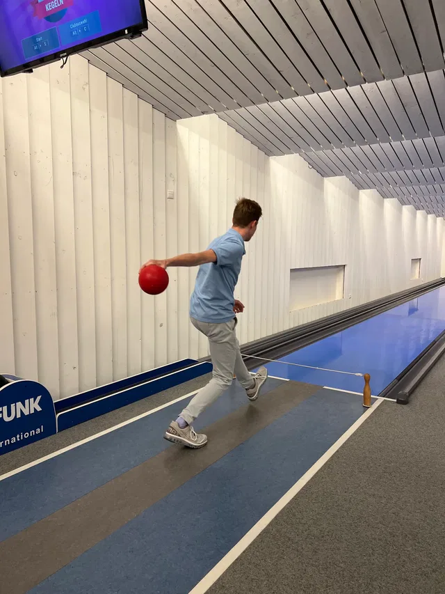 Spieler mit roter Kegelkugel vor der linken Bahn
