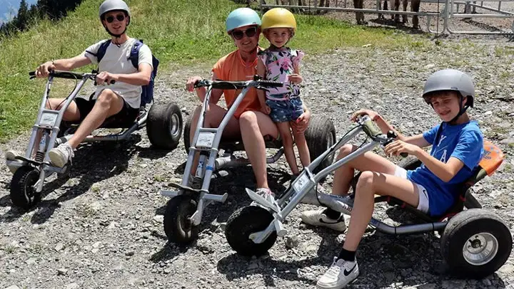Vier Gäste mit Helmen auf Mountaincarts an der Hörnerbahn.