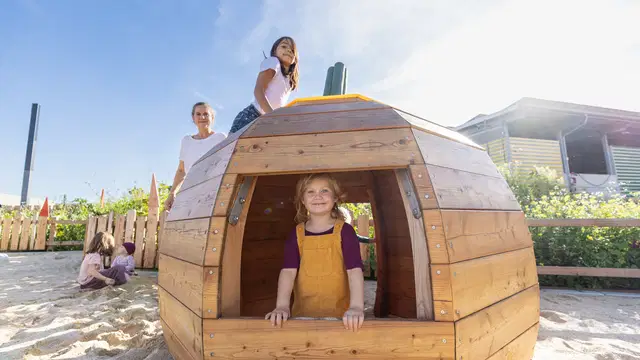 Kinder am runden Holzspielhaus auf dem Rapunzel-Spielplatz