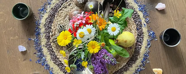 Blumenarrangement mit Obst auf einer geflochtenen Matte auf Holztisch