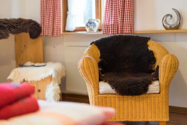Wicker-Sessel mit schwarzem Fellüberwurf vor Fenster im Wohnzimmer.