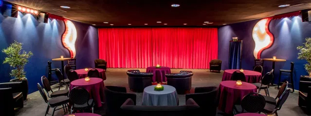 Saal EXTRA mit rotem Vorhang, Sesseln und Tischen
