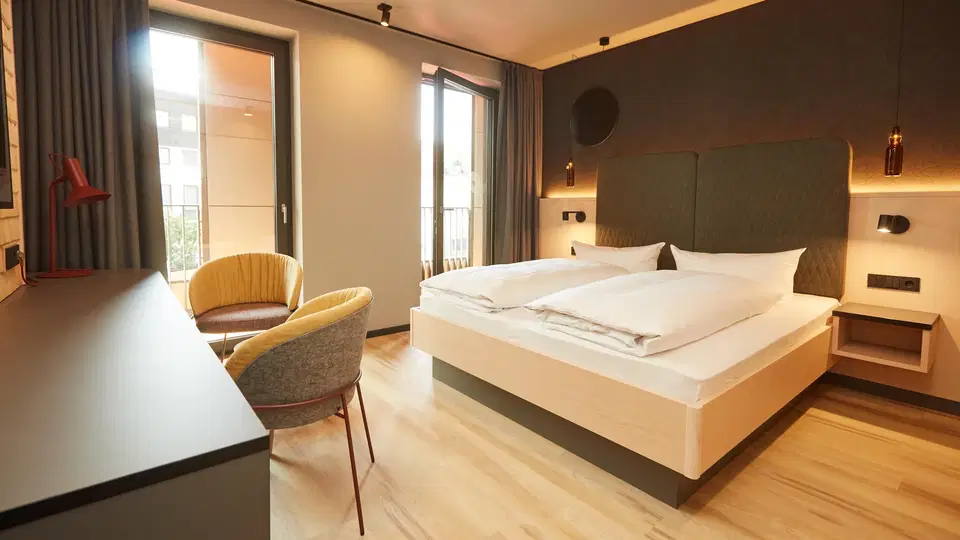 Doppelzimmer im Hotel Zum Goldenen Hirsch mit Balkon und zwei Sesseln.